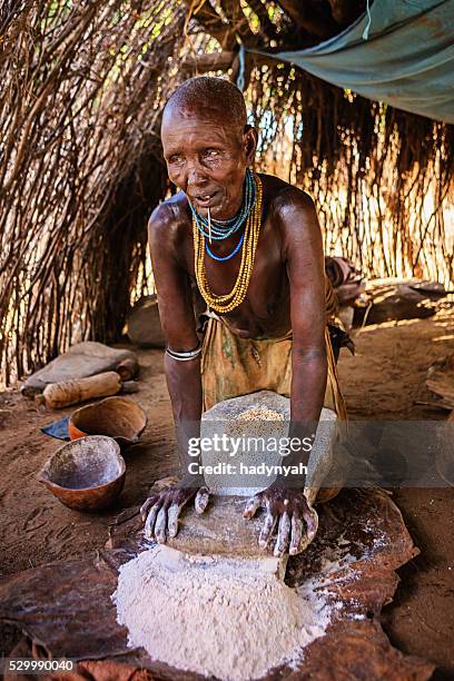 woman from karo tribe making sorghum flour, ethiopia, africa - karo 個照片及圖片檔