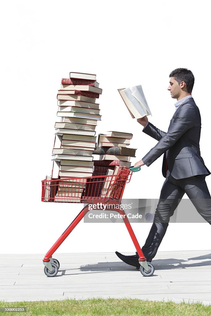 Man in suit walking with books in trolley