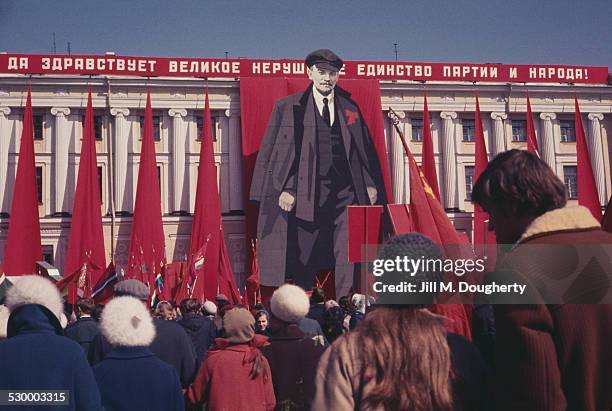 People gathered in front of a large banner of Vladimir Lenin on the front of a building in Russia, July 1991.