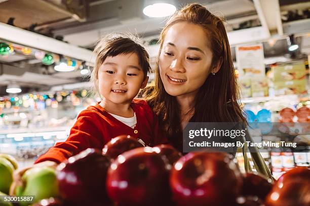 daughter & mom choosing fruit in supermarket - asian family shopping stock-fotos und bilder