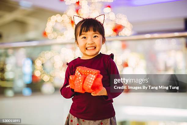 little girl similing joyfully with a gift in mall - christmas celebrations 2014 photos et images de collection