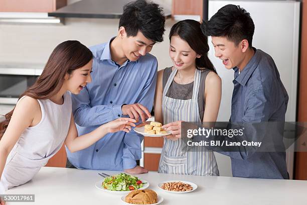 young woman cooking for her friends in the kitchen - almond joy stock pictures, royalty-free photos & images