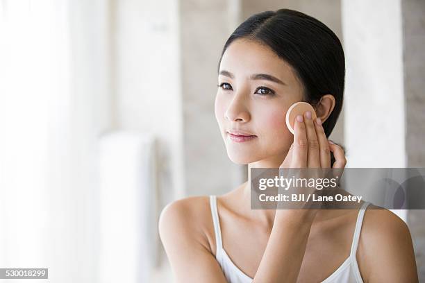 young woman applying facial powder - powder puff stock pictures, royalty-free photos & images