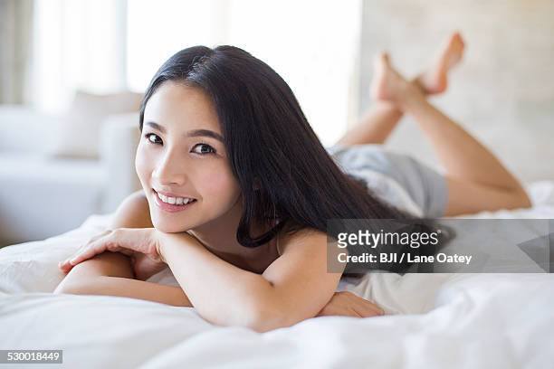 young woman lying on bed - chemise de nuit photos et images de collection