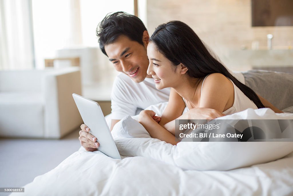 Young couple with digital tablet on bed