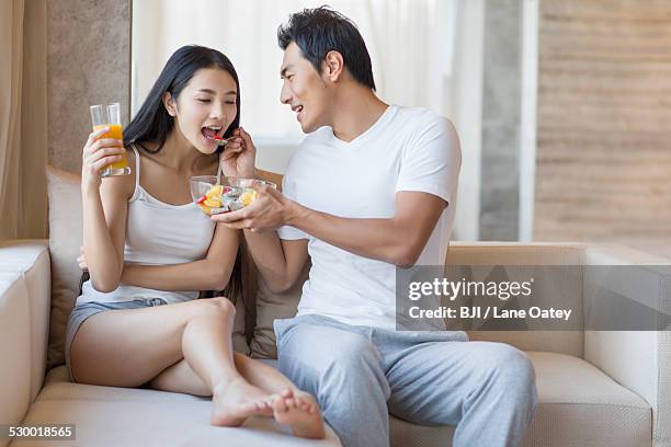 young man feeding his wife fruit salad - asian spoon feeding happy stock pictures, royalty-free photos & images