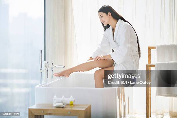 young woman sitting in bathroom - smooth curtain stock-fotos und bilder