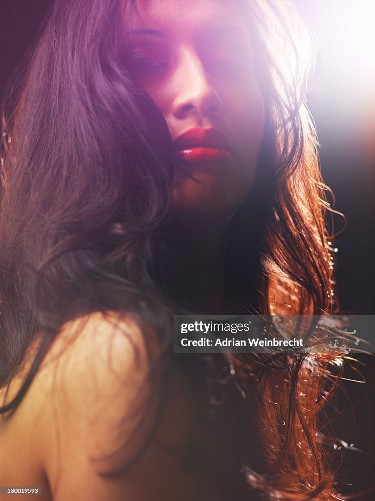 Young woman with long brown hair, backlit