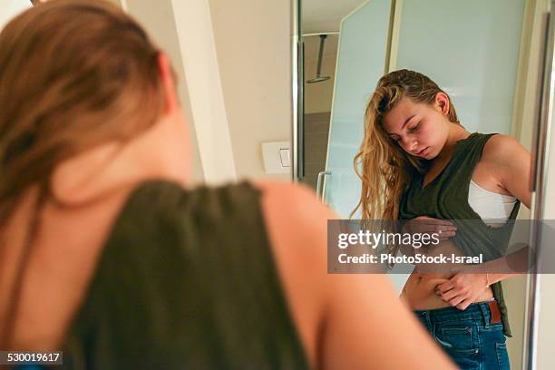 young woman pinching her waist - essstörung stock-fotos und bilder