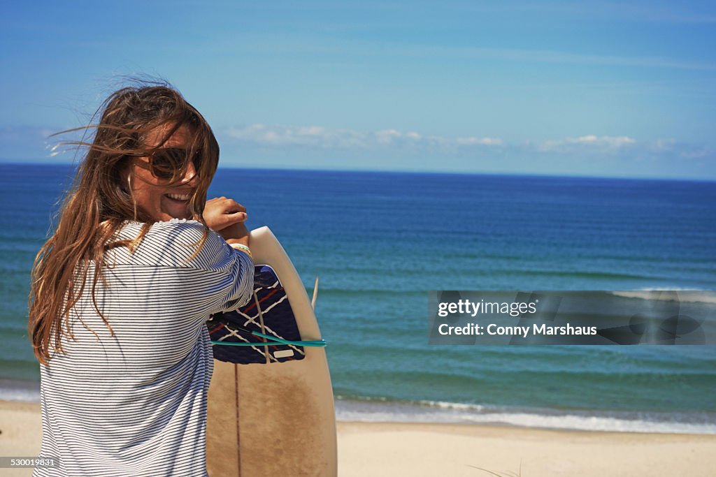 Woman with surfboard on beach, Lacanau, France