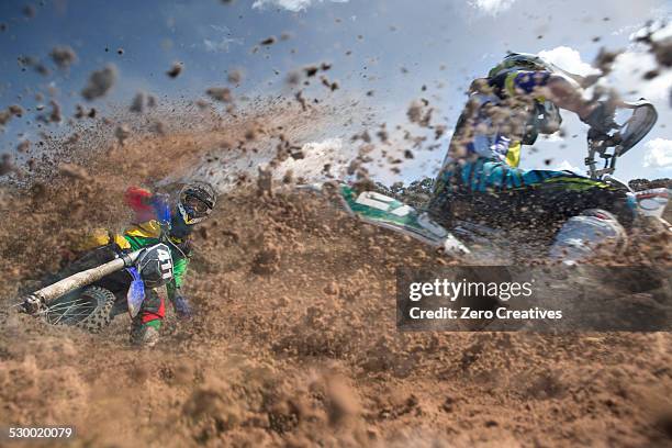two young male motocross riders racing through mud - motocross stock pictures, royalty-free photos & images