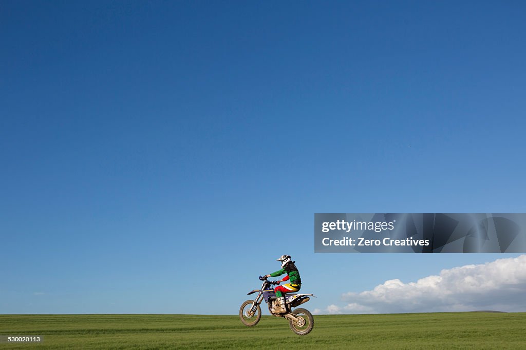 Young male motocross racer riding across field