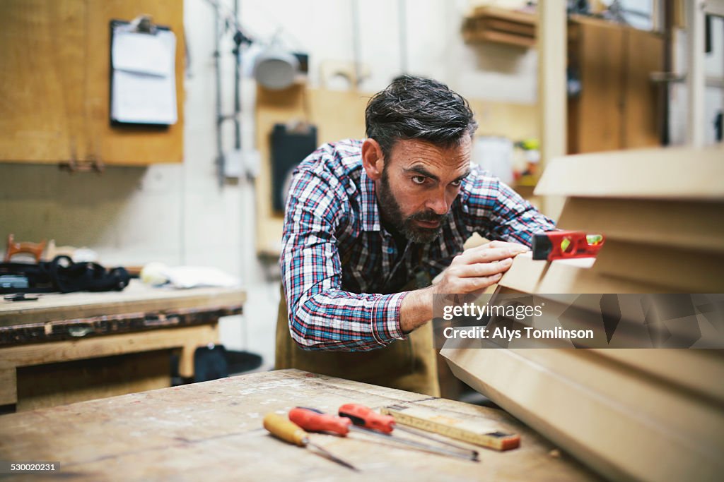 Mature craftsman using spirit level in pipe organ workshop