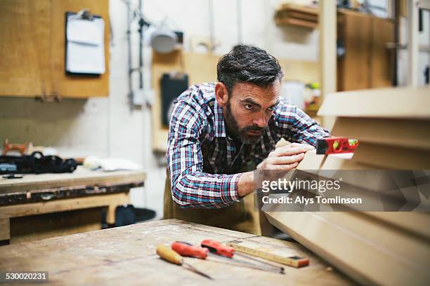 mature craftsman using spirit level in pipe organ workshop - business passion stock pictures, royalty-free photos & images