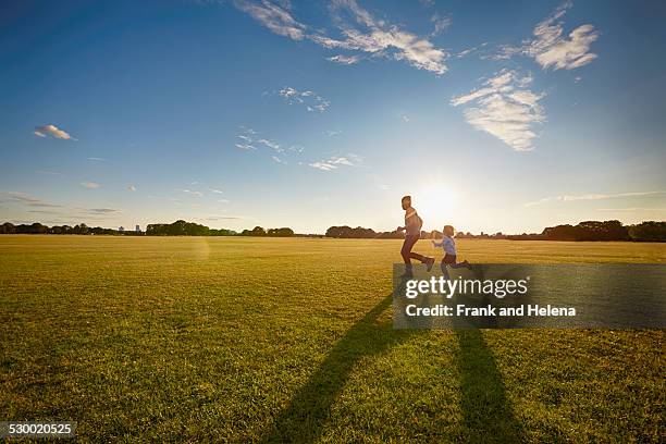 father and son out in the park - running in park stockfoto's en -beelden