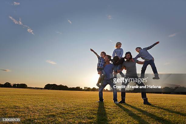 family enjoying outdoor activities in the park - mensenpiramide stockfoto's en -beelden