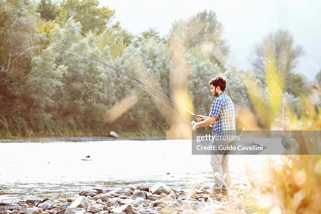 Young man fishing in river, Premosello, Verbania, Piemonte, Italy