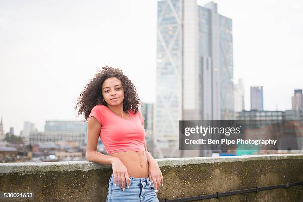 young woman leaning against wall - oberteil stock-fotos und bilder