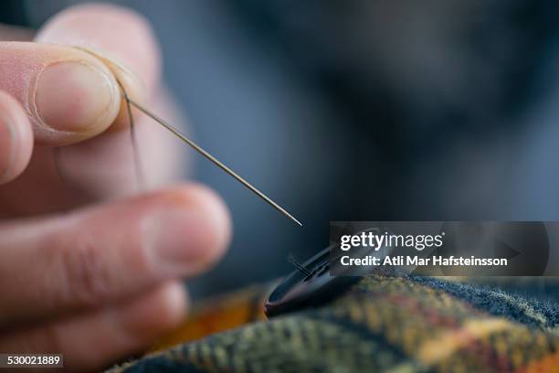 close up seamstress fingers sewing button onto tartan in workshop - repairing clothes stock pictures, royalty-free photos & images