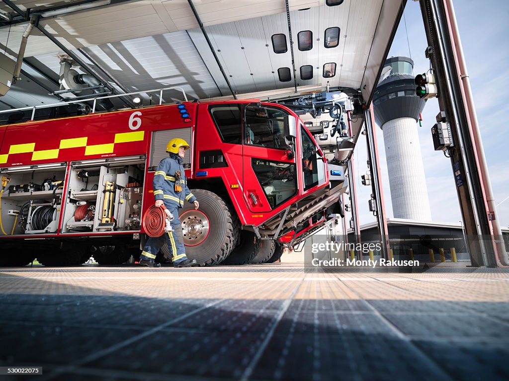 Fireman carrying equipment to fire engine in airport fire station