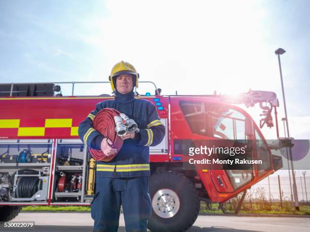 portrait of fireman in front of fire engine in airport fire station - firefighter uk stock pictures, royalty-free photos & images