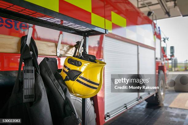 firemans helmet hanging by fire engine in fire station - brandweerwagen stockfoto's en -beelden