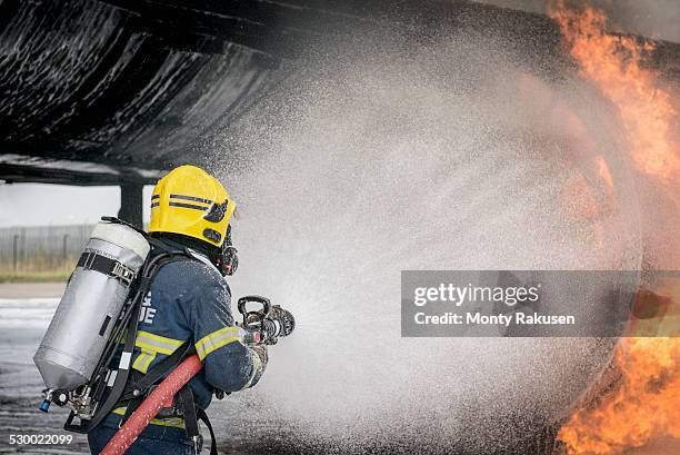 fireman spraying water on simulated aircraft fire at training facility - training aircraft stockfoto's en -beelden