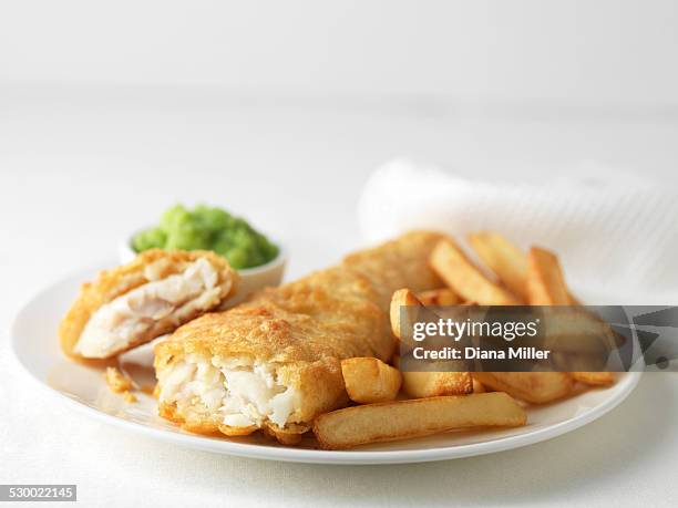 plate of battered cod and chips with mushy peas - fish and chips stock-fotos und bilder