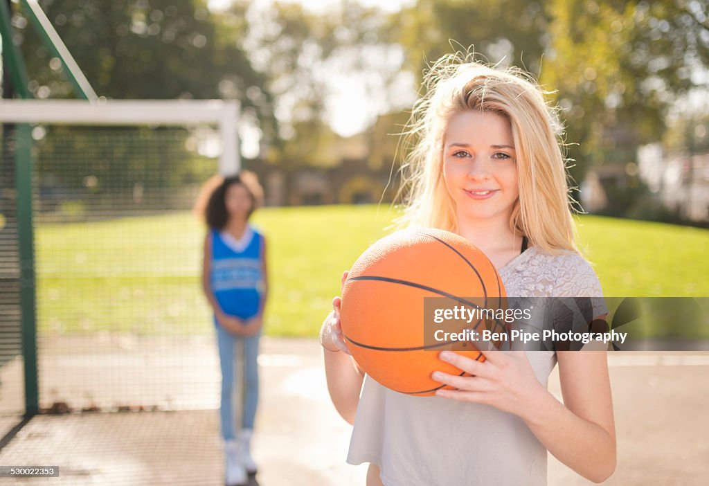 Portrait of young woman holding up basketball