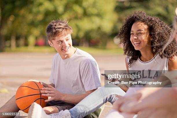 group of young adult basketball players sitting chatting - bethnal green fotografías e imágenes de stock