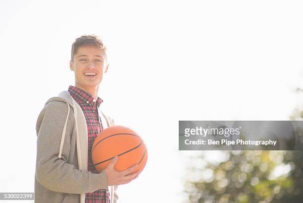 portrait of smiling young man holding basketball - bethnal green fotografías e imágenes de stock