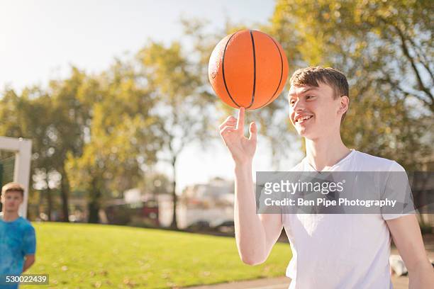 smiling young male basketball player balancing basketball on finger - bethnal green stock pictures, royalty-free photos & images