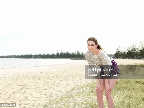 young woman bending forwards with hands in knees - hand on knee stock pictures, royalty-free photos & images