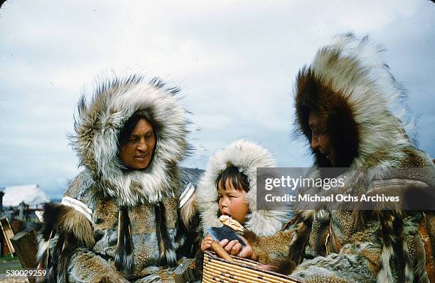 Two Inuit women and a baby pose in fur coats in Unalakeet, Alaska.