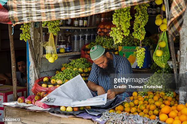 Mongla, Bangladesh A market trader reads a newspaper at his market stall with fruits on April 12, 2016 in Mongla, Bangladesh.