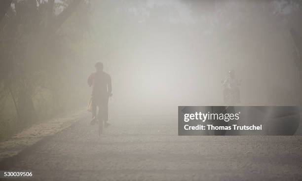 Mongla, Bangladesh A cyclist crossing a dusty and unpaved road in a rural region in the southwest of Bangladesh on April 12, 2016 in Mongla,...