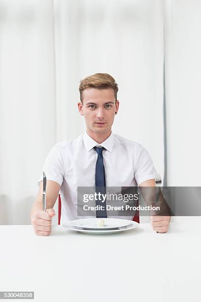 portrait of young man sitting at table with chocolate truffle - sitting at table looking at camera stock pictures, royalty-free photos & images