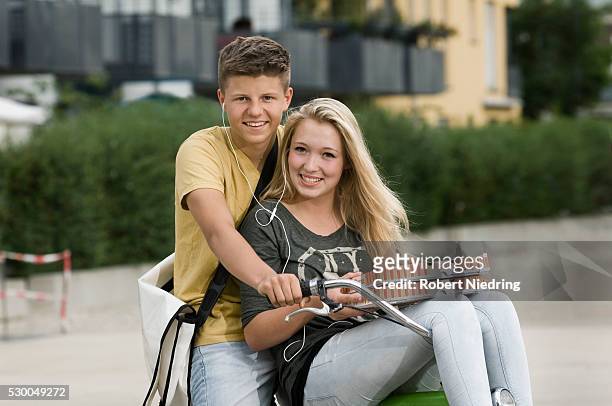 portrait of teenage couple listening music on bicycle, smiling - music box 個照片及圖片檔