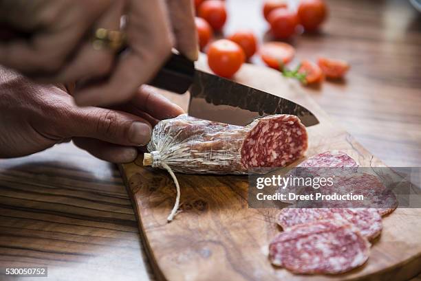 person's hand chopping sausage with knife, germany - salami stock-fotos und bilder