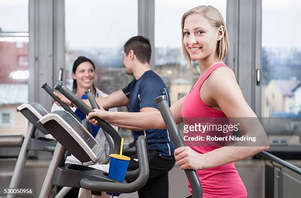 young woman on elliptical trainer in gym - happy caucasian woman on elliptical trainer at gym stock pictures, royalty-free photos & images