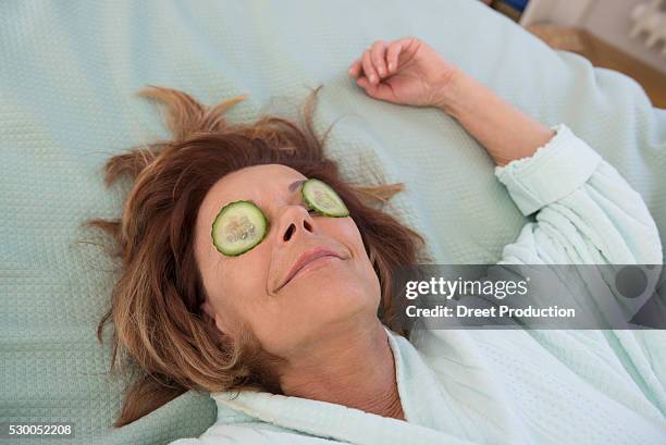 senior woman with cucumber slices on her eyes, munich, bavaria, germany - cucumber stockfoto's en -beelden