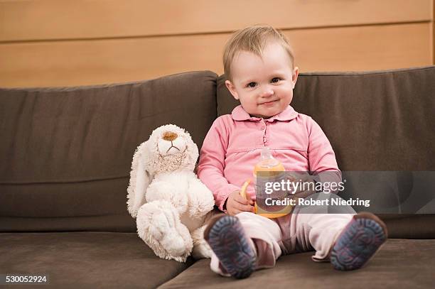 baby girl 18 months old sitting on sofa toy rabbit - baby bunny stock pictures, royalty-free photos & images