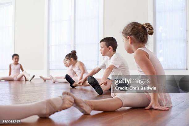 children sitting on floor practicing ballet position in ballet school - ballet boy stockfoto's en -beelden