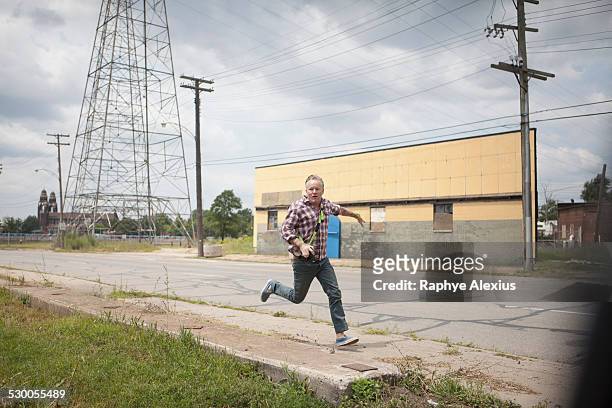 man running in panic along industrial road, detroit, michigan, usa - fuggire foto e immagini stock