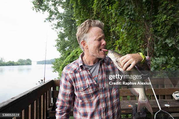 man sticking out tongue at catfish, river raisin, monroe, michigan, usa - michigan summer stock pictures, royalty-free photos & images