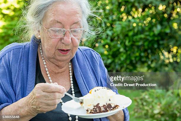 female senior eating cream cake - man eating pie stock-fotos und bilder