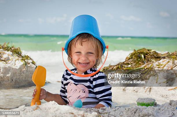 baby girl with bucket over head on beach, anna maria island, florida, usa - anna maria island stock-fotos und bilder