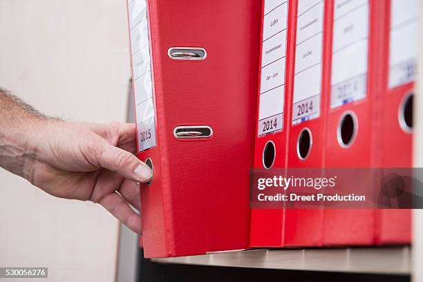 man taking confidential file from filing cabinet, munich, bavaria, germany - file cabinet stock-fotos und bilder