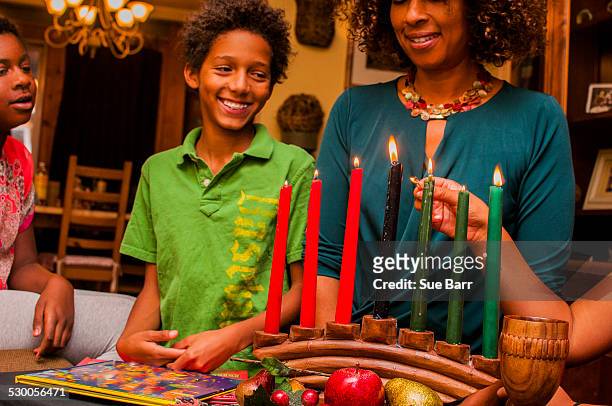 family lighting kinara candles, celebrating kwanzaa - kwanzaa celebration stock pictures, royalty-free photos & images