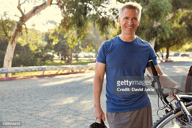 portrait of mature male cyclist in park - los angeles park stock pictures, royalty-free photos & images